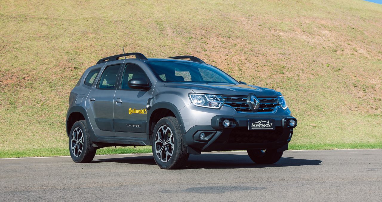 (foto diagonal da frente da Duster cinza com adesivo da Continental na porta)