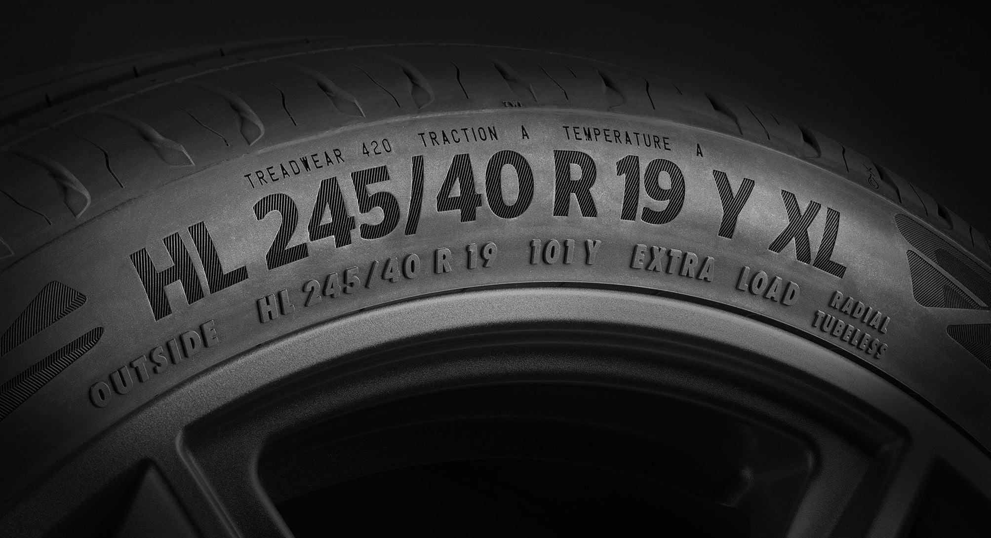 (foto em close da lateral de um pneu, mostrando em foco as medidas descritas no pneu)