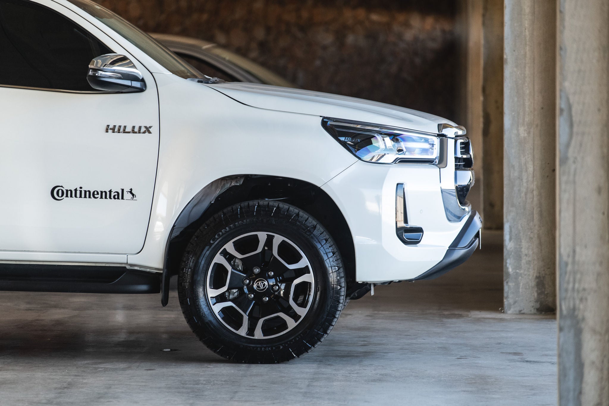 (foto lateral de caminhonete Hilux branca calçada com pneu Continental)