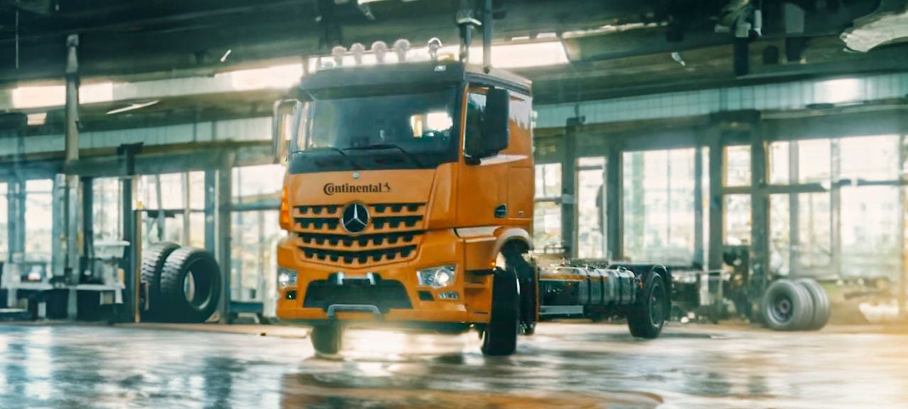 (Imagem de caminhão na cor amarelo Continental com adesivo da Continental em ambiente de teste industrial)