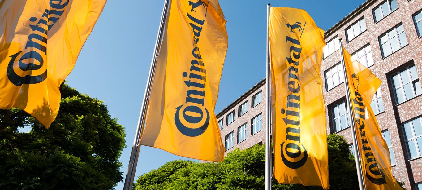 (foto de bandeiras com logotipo Continental em frente a prédio)