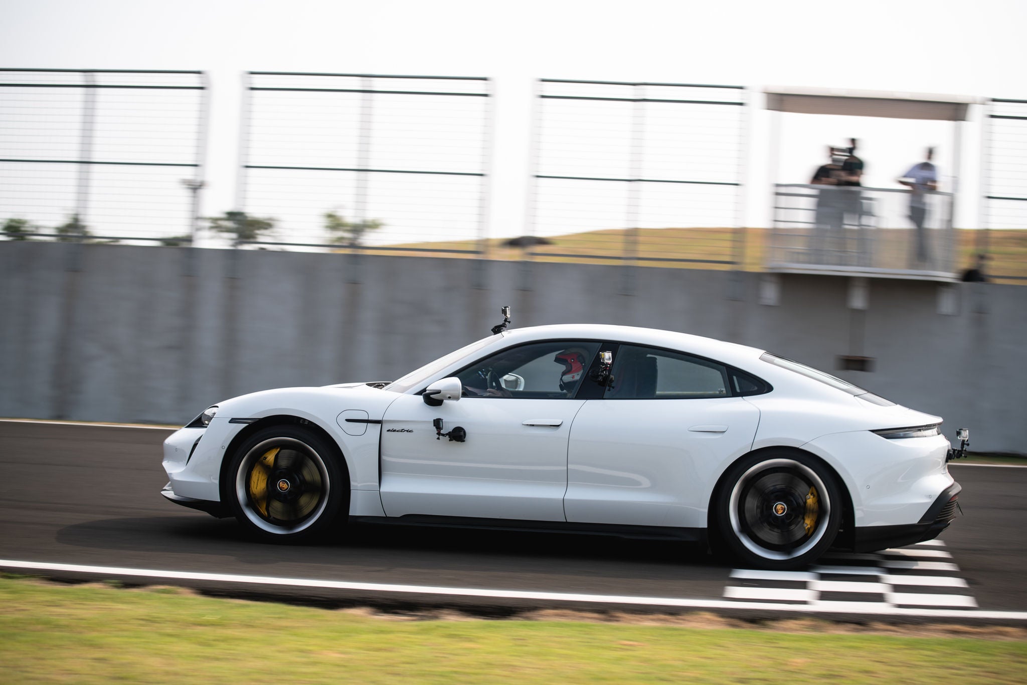 (imagem de Porsche elétrico branco com pneus Continental, passando em alta velocidade a faixa de chegada da pista)