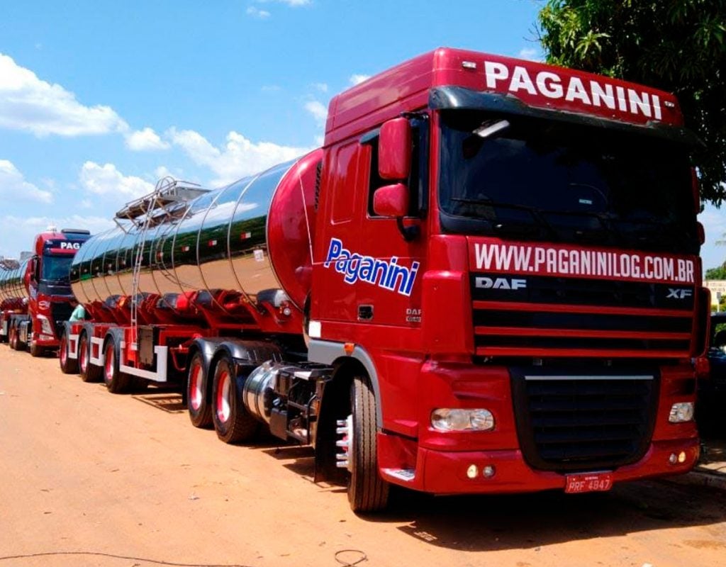 (foto de caminhão vermelho com adesivo da Paganini - cenário de céu com poucas nuvens e rua de terra)