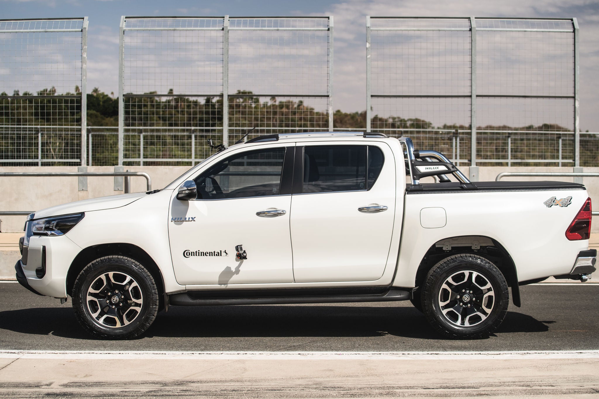 (foto lateral de caminhonete Hilux branca calçada com pneu Continental)