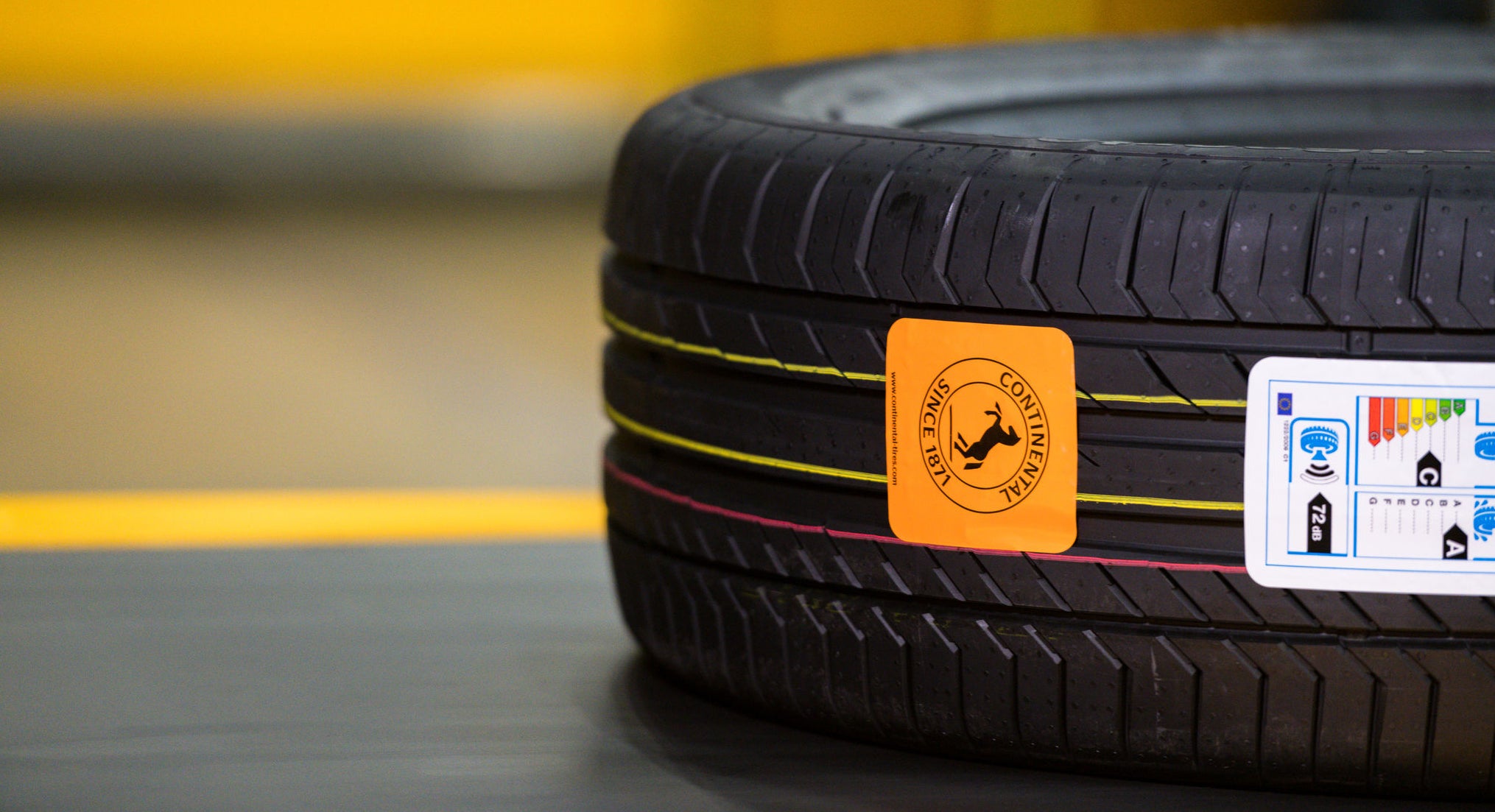 (foto de pneu deitado na esteira de produção, com etiqueta com ícone da Continental colado na banda de rodagem)