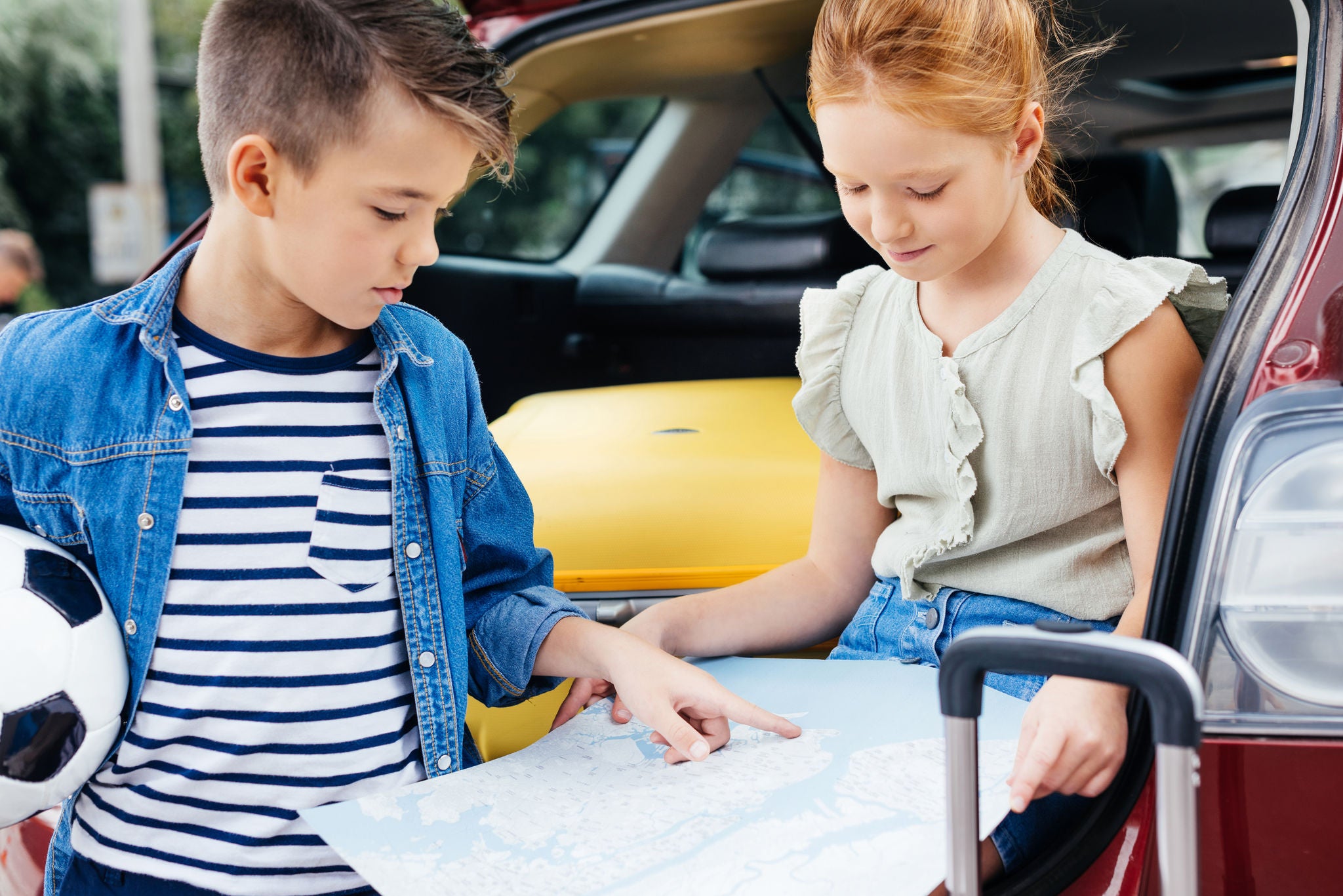 (um menino e uma menina apontando em um mapa de papel)