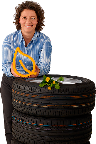 (foto da Dra Carla Recker apoiada em pilha de pneu, segurando objeto laranja em forma de folha)
