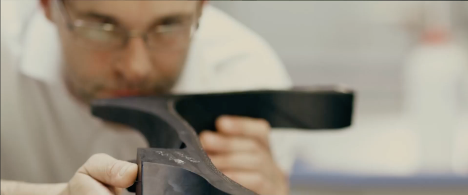(Foto de homem com óculos olhando de perto uma os componentes cortados de uma secção de pneu)