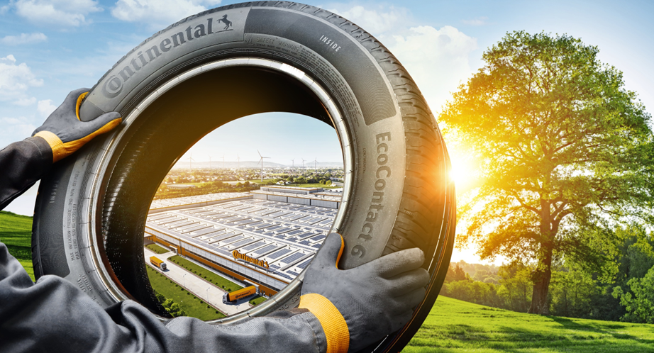 (Imagem de mãos segurando pneu Continental sustentável com fundo da fábrica e árvore)