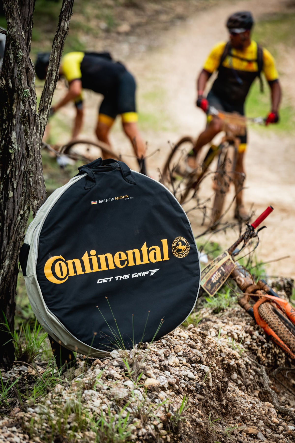 (Imagem de ciclistas desfocados no fundo da foto e em foco na frente, mala de roda de bicicleta adesivada com Continental )