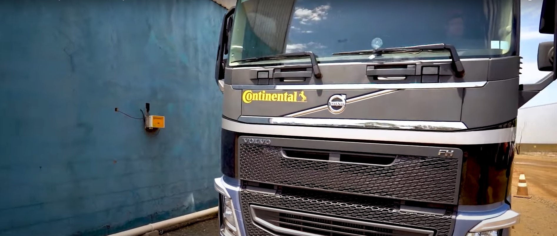 (foto de caminhão da Volvo com adesivo Continental passando ao lado de parede com antena Conti Yard Reader)