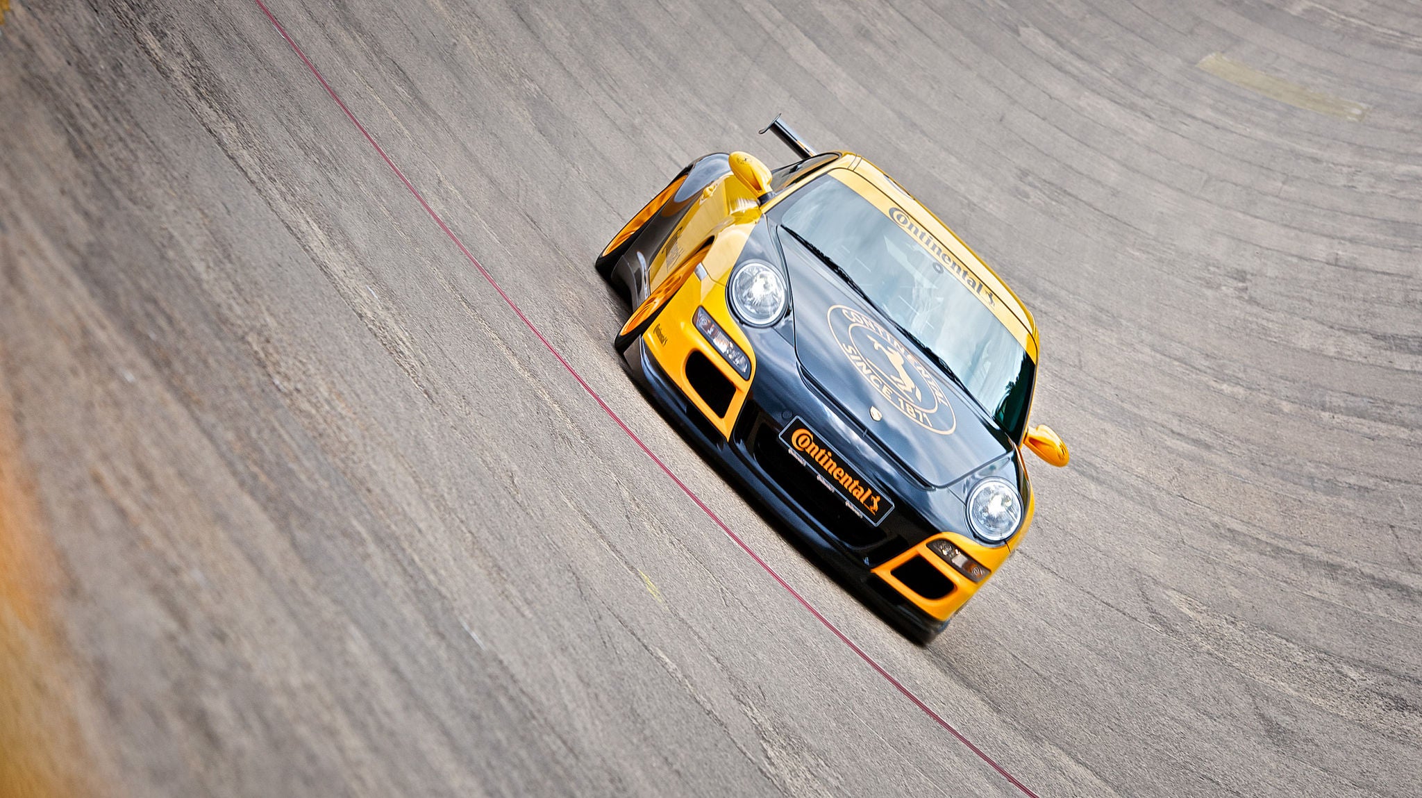 (imagem de Porsche adesivado com Continental durante curva inclinada na pista de teste Contidrom)