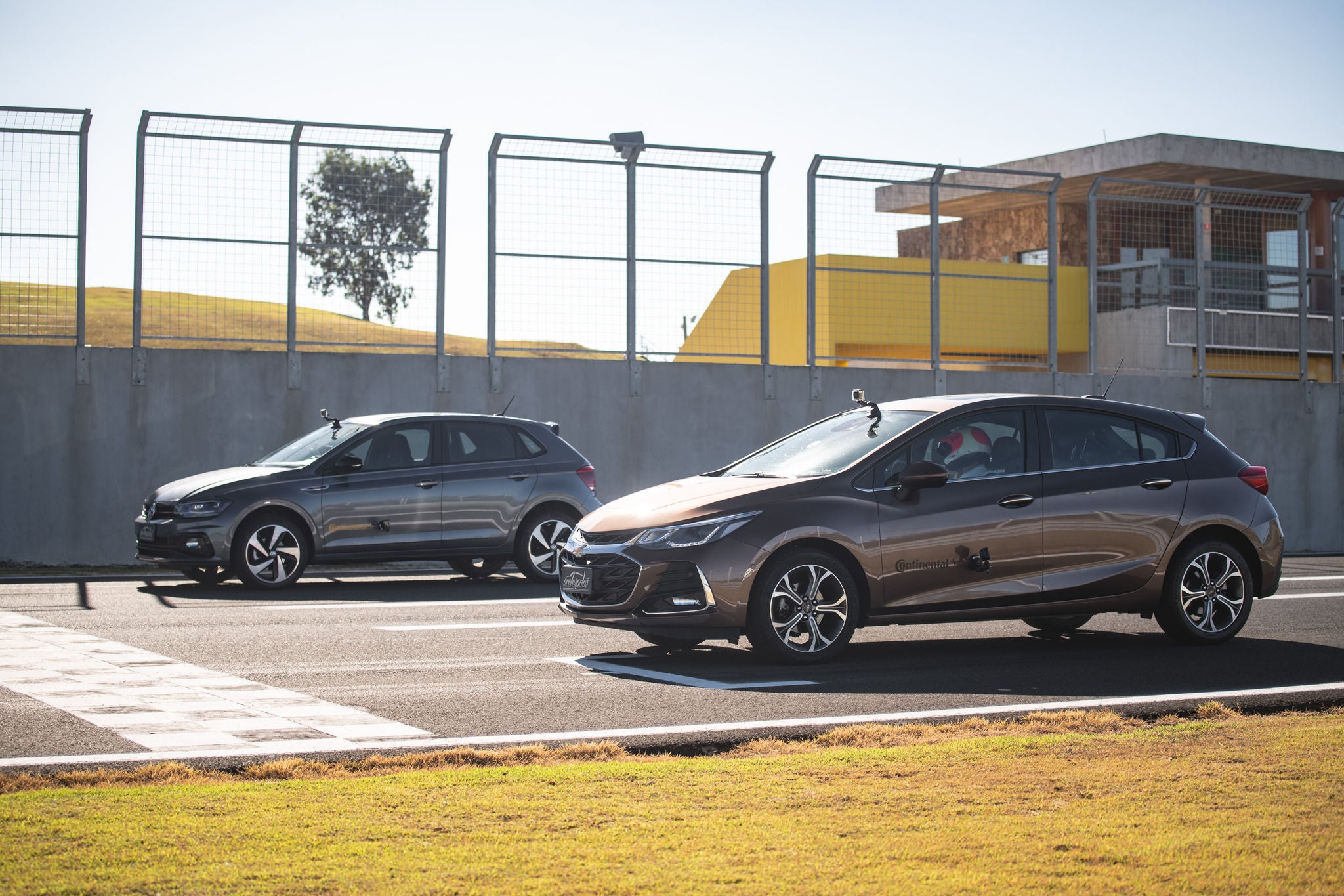 (foto lateral de Polo e Cruze calçados com pneu Continental, parados na pista na linha de largada)