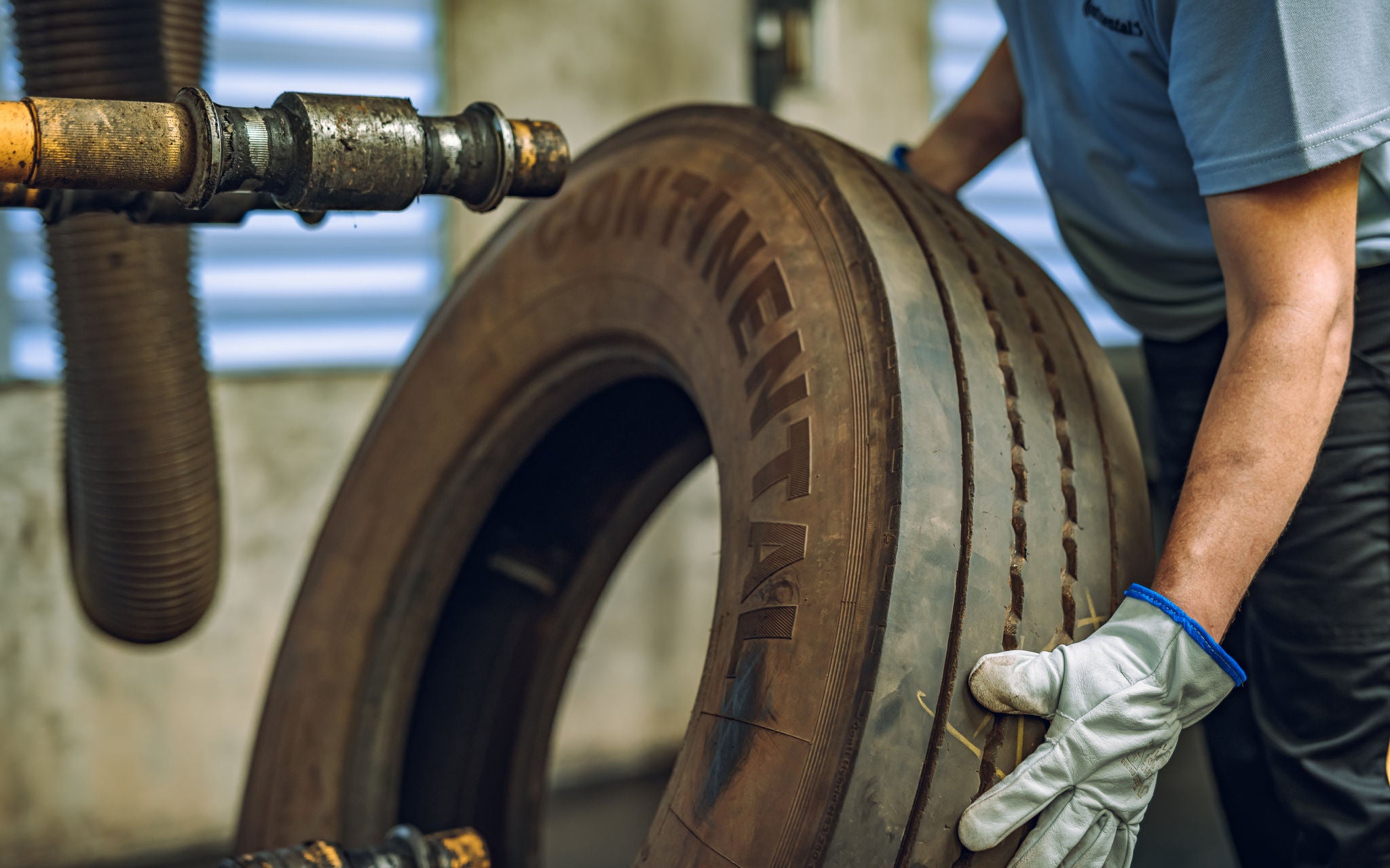 (foto de pessoa com luva segurando um pneu de carga para ser utilizado em máquina)