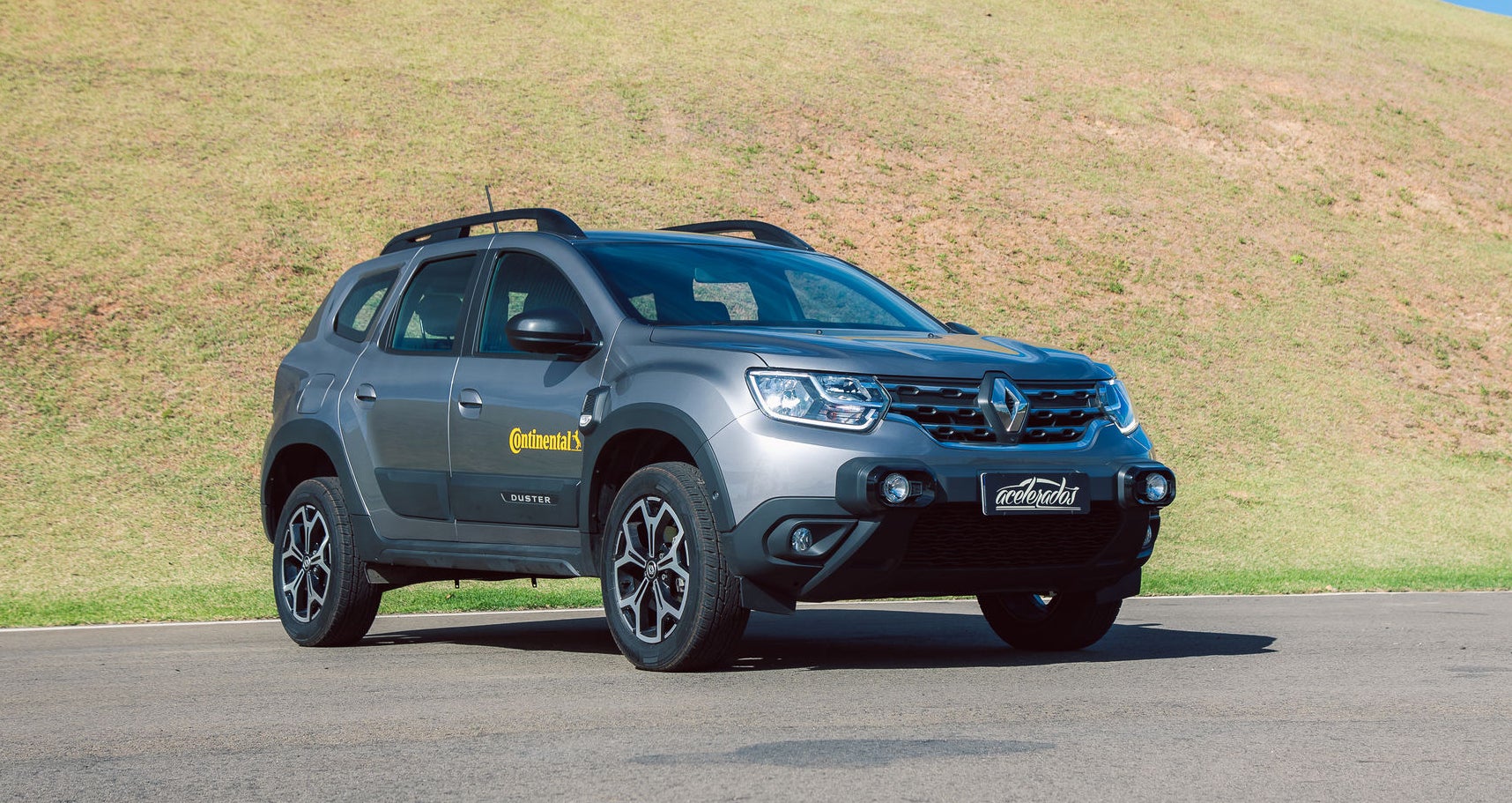 (foto diagonal da frente da Duster cinza com adesivo da Continental na porta)