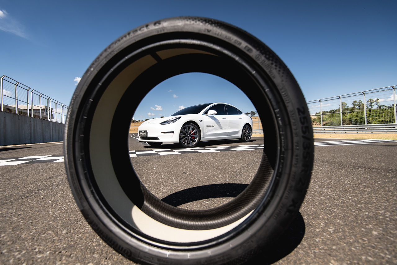 (imagem de pneu Continental com tecnologia ContiSilent e ao fundo Tesla Model 3 Performance branco com pneus Continental)