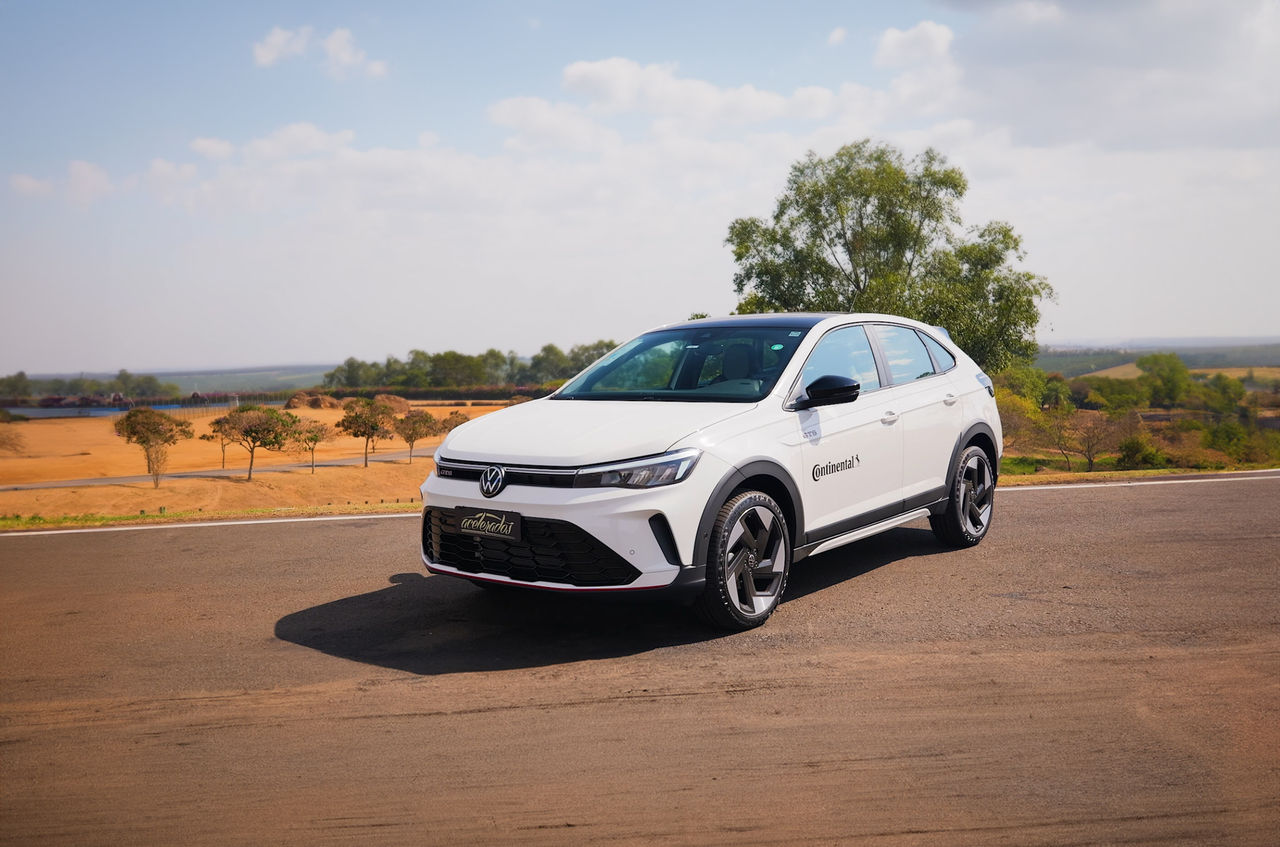 (imagem de um Nivus GTS 2025 branco, com adesivo do logo da Continental em preto na porta, equipados com pneus originais PremiumContact 6 da Continental, fundo cenário sem árido com poucas arvores e céu aberto, se encontra em uma pista de asfalto)