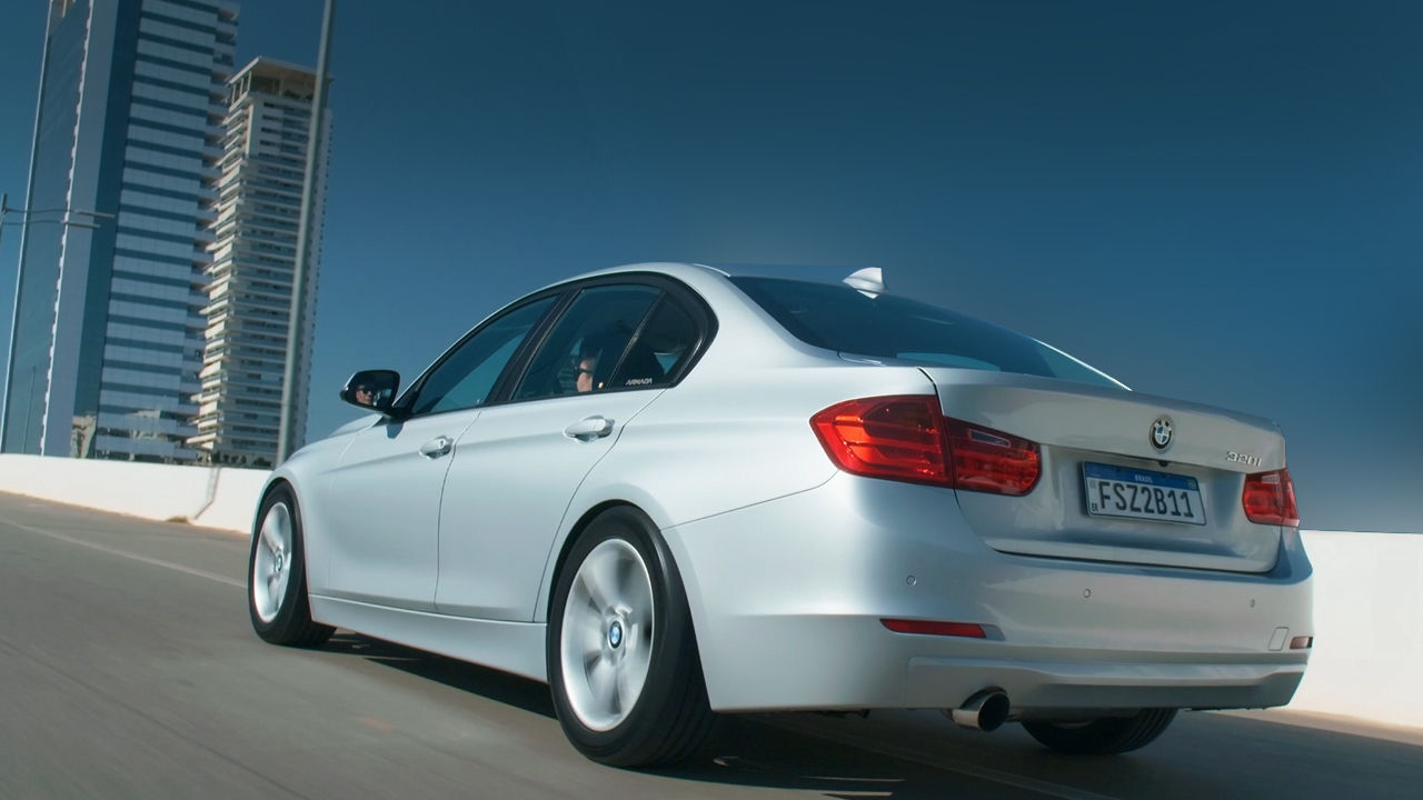 (imagem de uma BMW 320i prata andando em uma ponte)