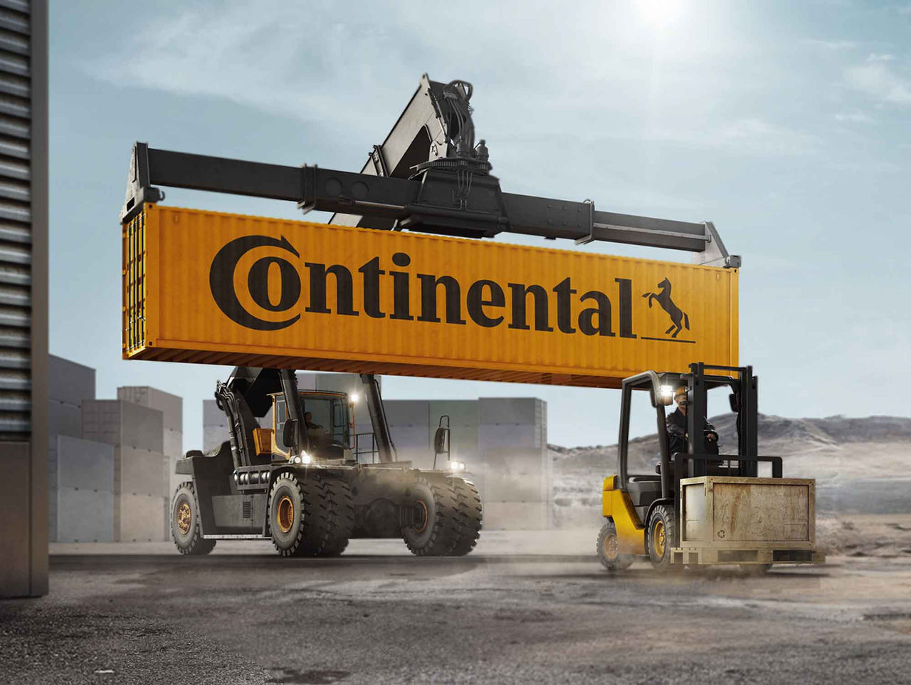 (A imagem apresenta um cenário industrial onde dois veículos de carga com pneus Continental estão em ação. No centro, uma empilhadeira guindaste grande que levanta um contêiner de metal amarelo com o logotipo da "Continental", com o cavalo em destaque. O guindaste tem um braço longo e robusto, demonstrando sua capacidade de levantar cargas pesadas, enquanto o contêiner permanece suspenso no ar. À direita, uma empilhadora amarelada está em movimento, transportando material em uma plataforma inferior, que parece ser feita de madeira ou metal. O fundo é composto por estruturas de concreto, com um céu claro e alguns nublados suaves. O ambiente transmite uma sensação de atividade intensa e eficiência operacional. O solo apresenta marcas e poeira, indicando o tráfego de veículos pesados)